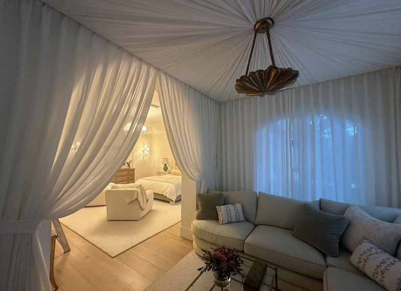 Gathered white canopy ceiling and sheer curtains opening into a bedroom
