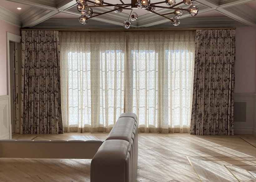 Floral side drapes with ivory lace sheers under a glass chandelier